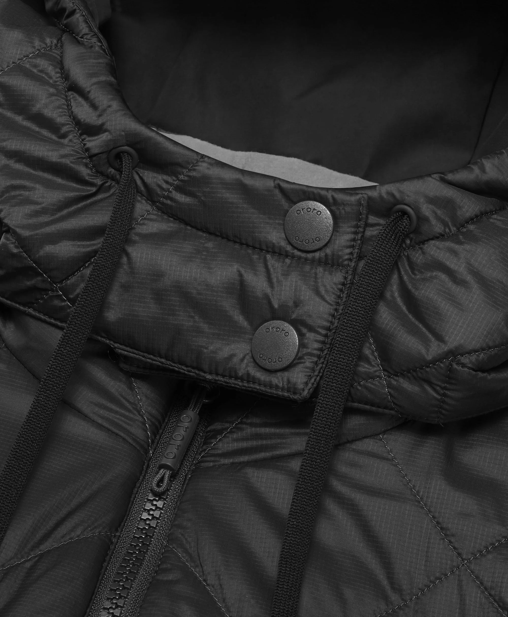 Close-up of a black quilted jacket with buttons and zipper